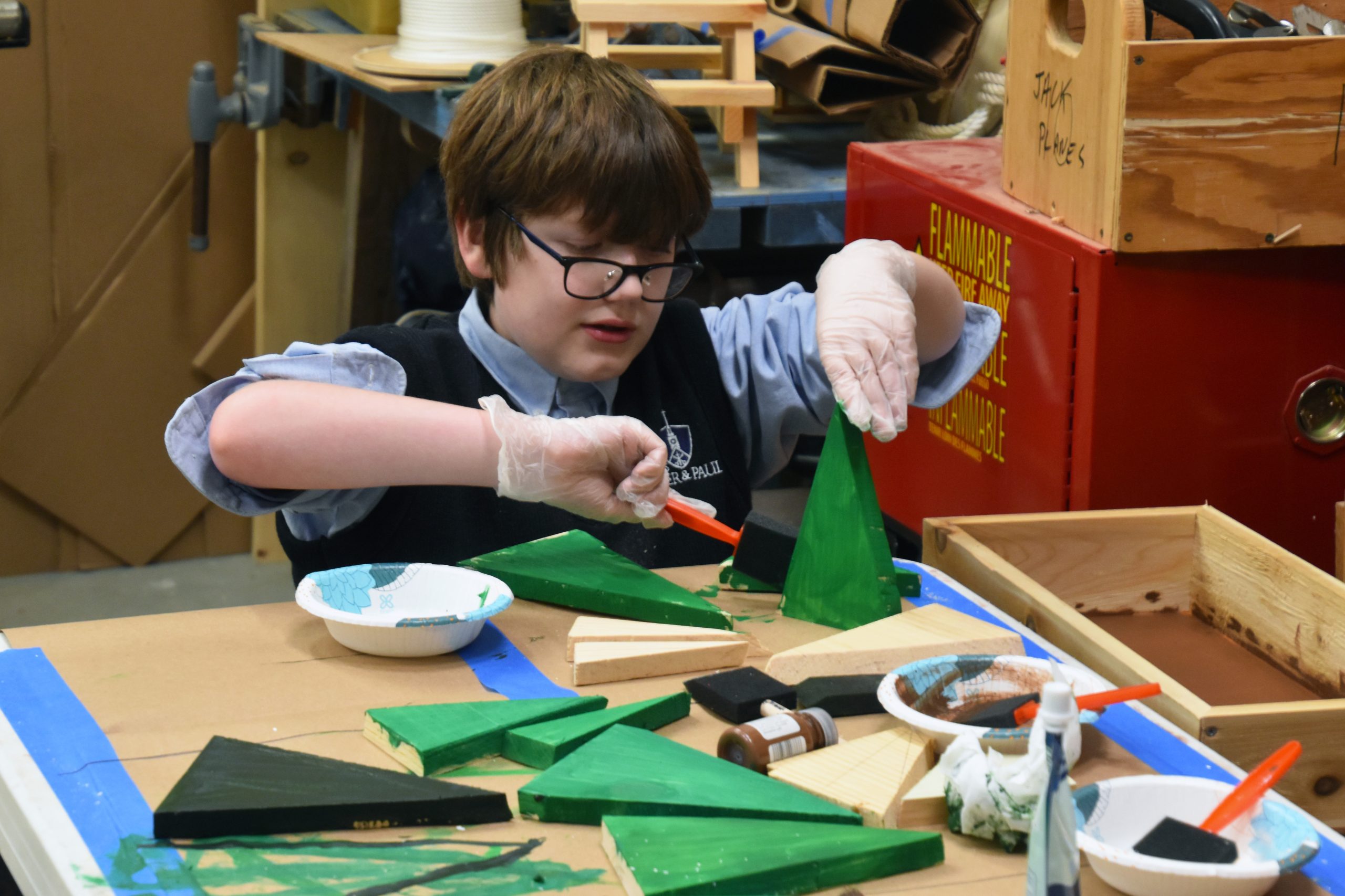 A child paints small, wooden Christmas trees.