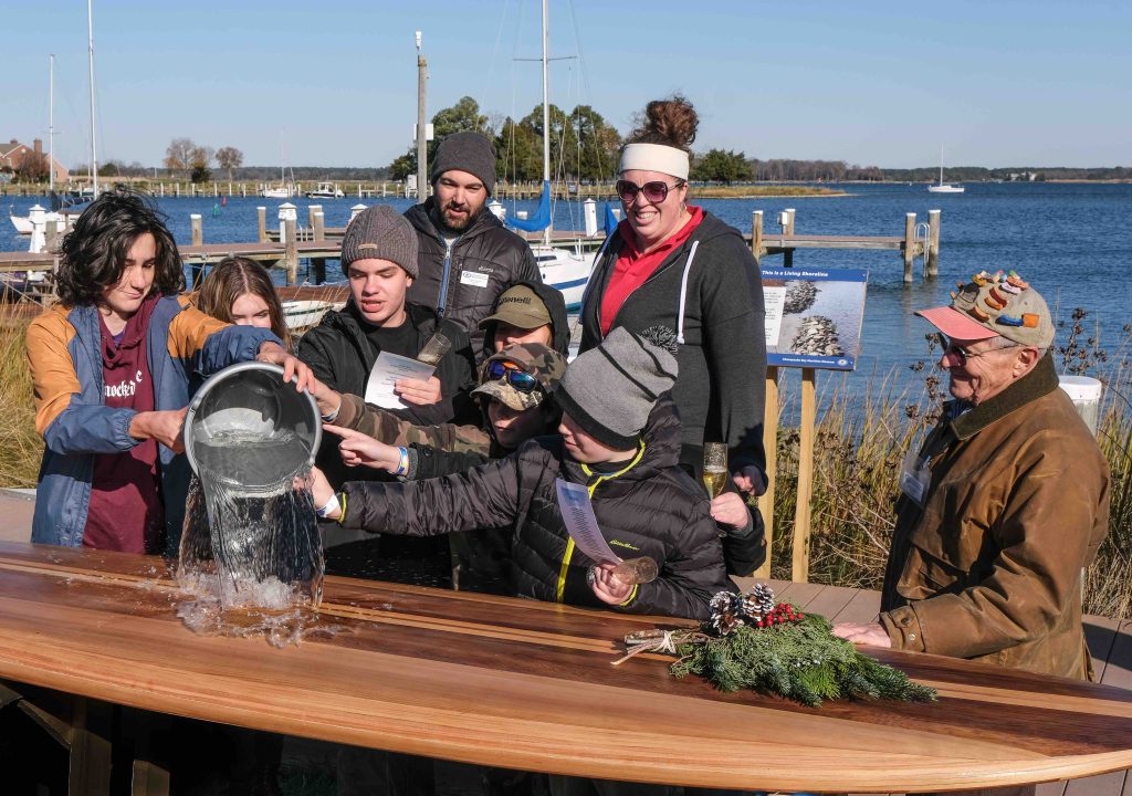 Students in the Rising Tide program celebrated the completion of their stand-up paddleboard project with a ceremonial splashing. (Photo by George Sass)
